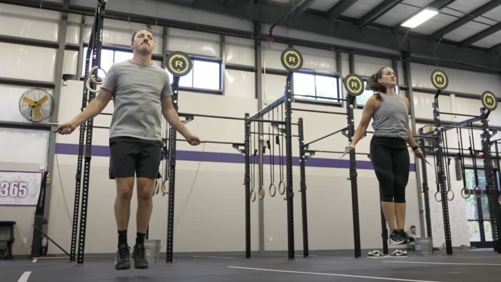 a man and woman doing double-unders in a gym