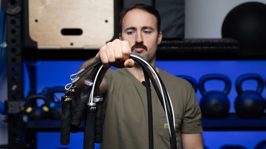 a man holding several jump ropes and looking at them as if deciding which one to use